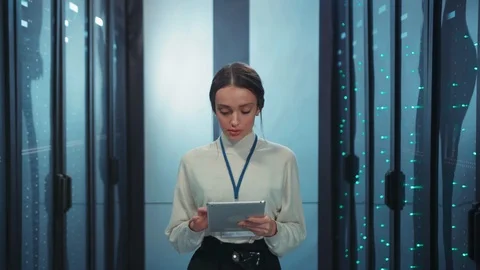 IT engineer woman running diagnostics on digital tablet in rack server room Видео 119736932