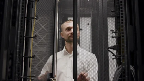 IT engineer working with laptop before open server rack in room Stock Footage 107148059