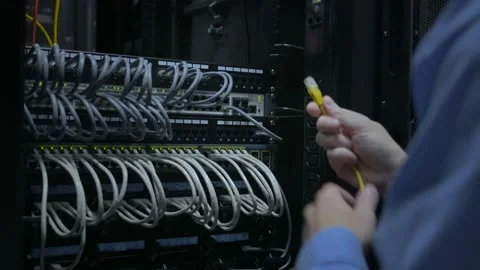 An IT engineer's hand plug in the network cable to the network switch Stock Footage 96528019