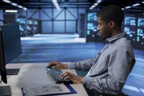 IT expert coding at computer desk, safeguarding data center Foto stock
