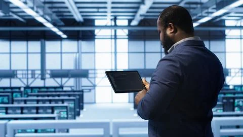 IT expert in server hub facility looking for network bugs with tablet Foto stock