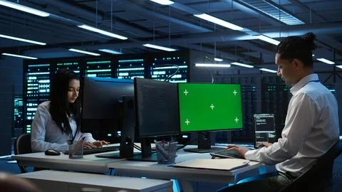 IT expert in server room tracking network traffic with chroma key PC Stock Photos