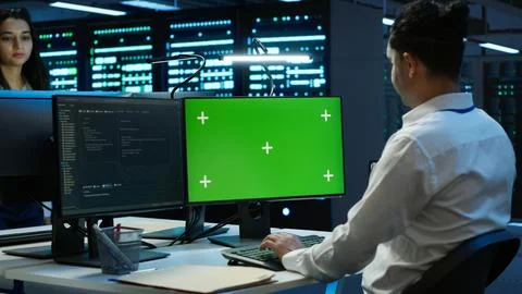 IT expert in server room tracking network traffic with chroma key PC Stock Photos