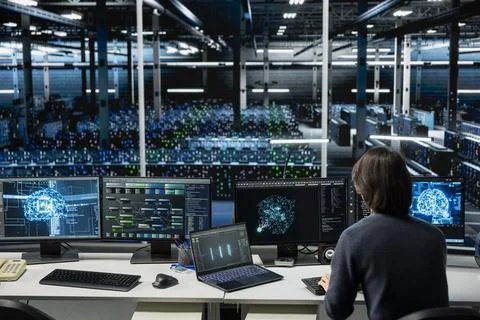 IT expert using PC in high tech server hub with gear supporting deep learning Stock Photos