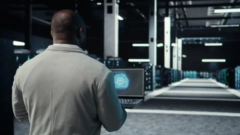 IT expert walking in server hub using laptop to enhance AI model accuracy Stock Footage 311898439