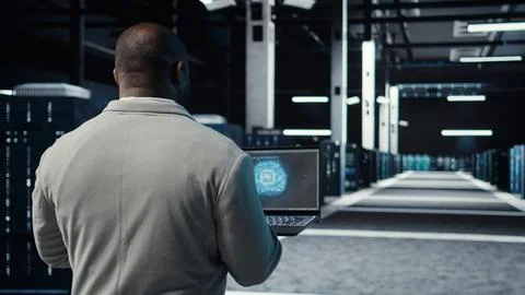 IT expert walking in server hub using laptop to enhance AI model accuracy Stock Photos