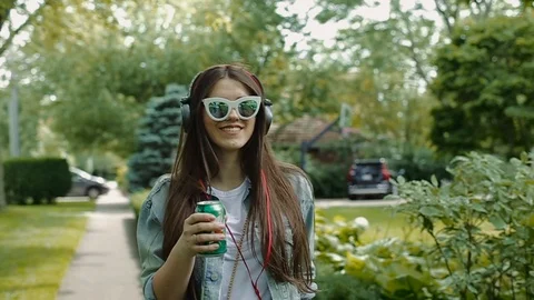 It is front image of young female walking in park drinking soda. Stock Footage 104315707