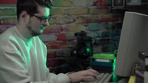 IT Guy From 1990's Working on Desktop Computer Surrounded With VHS Cassette Stock Footage 303405792