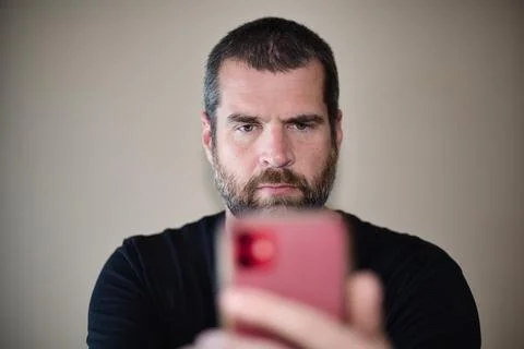 IT Guy Looking at Cell Phone - Serious Fotos de archivo