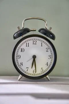 It is half past five. The time is 5:30 am or pm. Retro clock on a wooden table. Foto stock