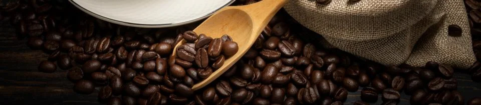 It has roasted coffee beans with a stack of wooden spoons on wooden table. .. Stock Photos