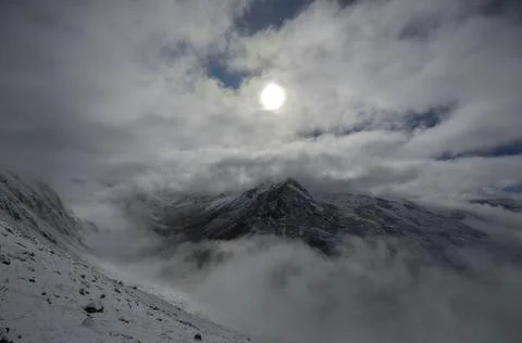 It has snowed on the mountains. There is sun, blue sky and clouds. Stock Photos