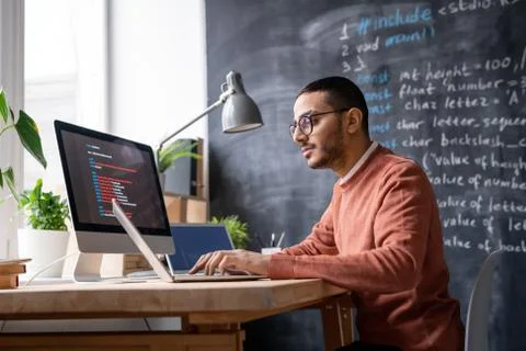 It-manager sitting in front of laptop in office and analyzing coded information Stock Photos