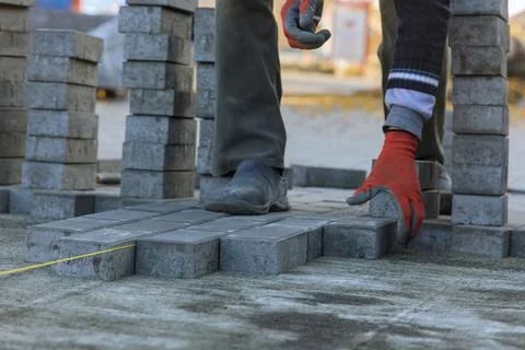 It is the master who is laying gray concrete paving brick slabs on sand Stock Photos