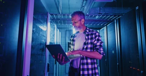 IT Professional Using Laptop in Neon-lit Server Room 스톡 동영상 280533154