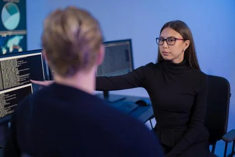 IT professionals collaborating in a secure operations center with code displayed Stock Photos
