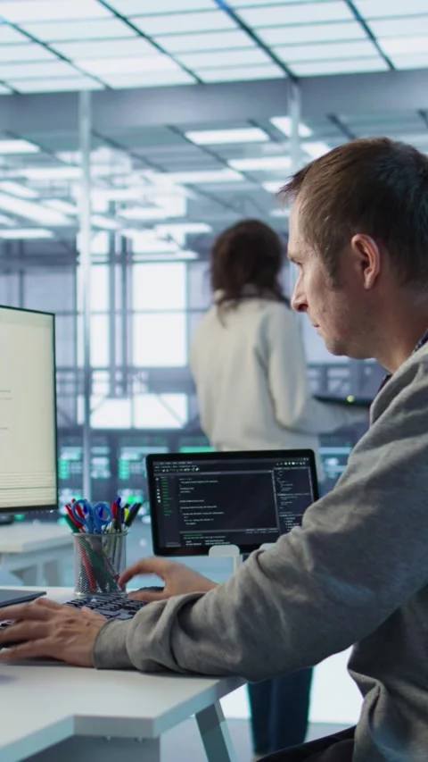 IT programmer arriving at work in data center, sitting at PC desk Stock-Footage 319575763