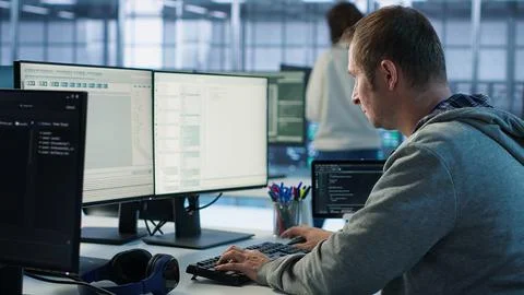 IT programmer arriving at work in data center, sitting at PC desk Stockfoto's