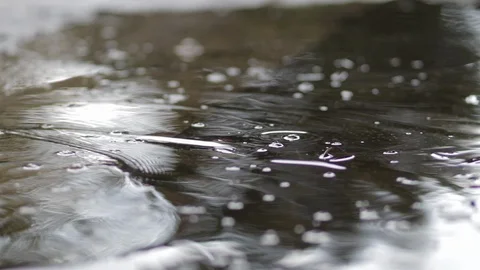 It is raining outside. Rain drops break in puddle. Slow motion. Close up. Stock Footage 121259002