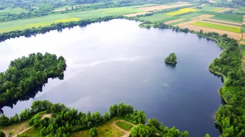 As it rises drone captures a beautiful calm lake surrounded with colorful fields Stock Footage 269165064