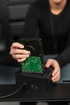 It security technician inspects a hard drive during data recovery in a technical Stock Photos