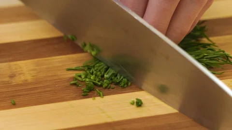 It is slicing of the dill by a kitchen steel knife on a bamboo cutting board. Stock Footage 128329079