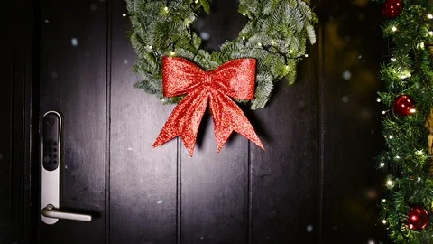 It snows on front door decorated with christmas wreath and a big red bow Stock Footage 99725545