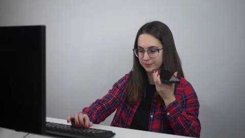 The IT specialist records a voice message. Young woman in glasses and a shirt in Stock-Footage 231402904