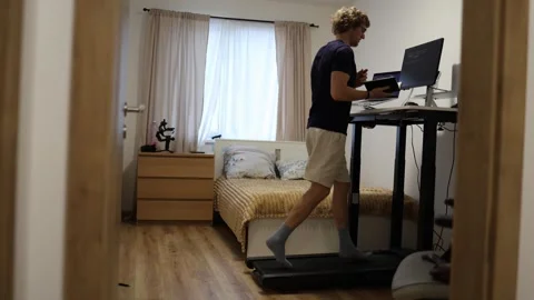 IT specialist runs on treadmill while studying programming at home Vídeo Stock 347269945