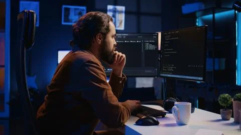 IT specialist sitting at computer desk, working on desktop PC 写真素材