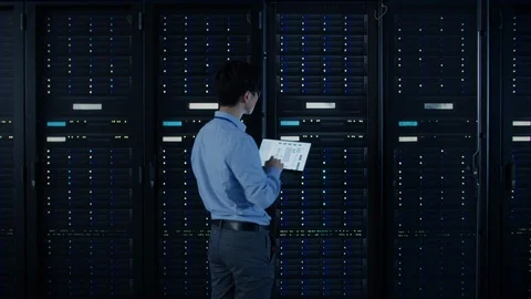 IT Specialist Standing In front of Server Racks with Laptop, He Activates Data Stock Footage 103279080