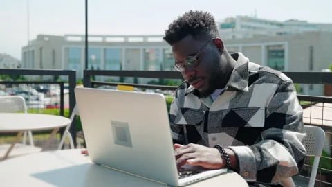 IT specialist is working remotely from cafe, black man is typing on keyboard of Stock Footage 224529517