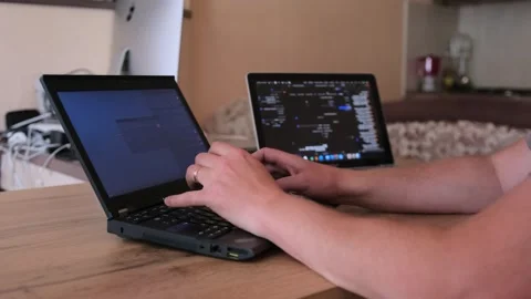 IT specialist working on two laptops typing program code on keyboard. Stock-Footage 243580790