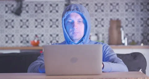 It specialist works at home at a computer. Hooded programmer coding on laptop Video stock 238007664