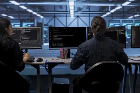 IT specialists at PC desk in server room deploying error checking utilities Stockfoto's