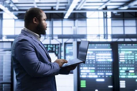 IT staff member working in data center housing storage rackmounts hardware Stockfoto's