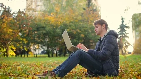 It startup programmer man working in the park using laptop sitting on the grass Stock Footage 70683709