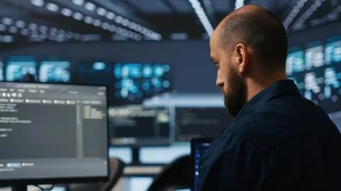 IT supervisor overseeing server room, running code on PC, troubleshooting rigs Stockfoto's
