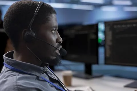 IT support worker in data center talking in headphones mic, doing yearly checkup Stockfoto's