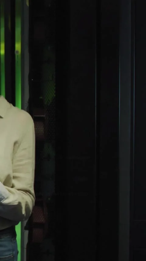IT tech standing in DC, tapping phone, checking servers, console text responding Stock Footage 331738668