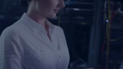 IT tech typing laptop starting teal shapes hiding then showing racks cam pulling Stock Footage 335739227