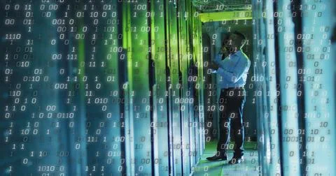 IT technician analyzing server rack in data center corridor, with tablet and Foto stock