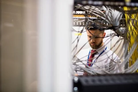 IT technician is examining network cables with handheld device in flat design Stock Photos