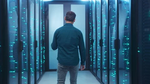 IT technician walking in futuristic database server corridor inspecting Stock Footage 119842526