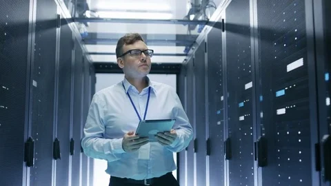 IT Technician Walks Through Rows of Server Racks in Data Center.  Stockbeeldmateriaal 74631105