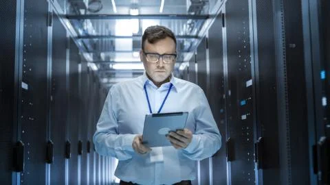 IT Technician Walks Through Rows of Server Racks in Data Center. Simultaneous Stock Photos