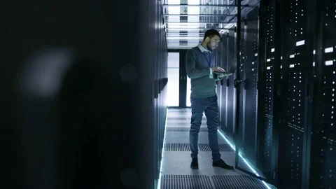 IT Technician Works on Laptop in Big Data Center full of Rack Servers.  Stock Footage