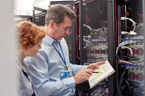 IT technicians with clipboard examining panel in server room Foto stock