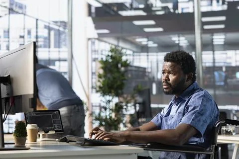 IT worker with disability in wheelchair optimizing code Foto stock