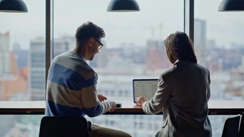 It worker joining colleague opening computer at big window open space back view Stock Footage 335247432